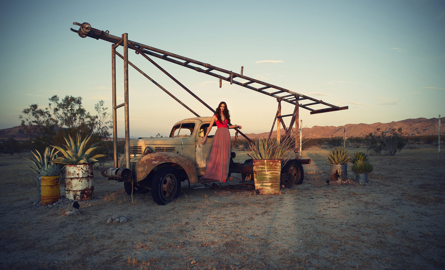 Red headed woman in evening gown standing on truck relic