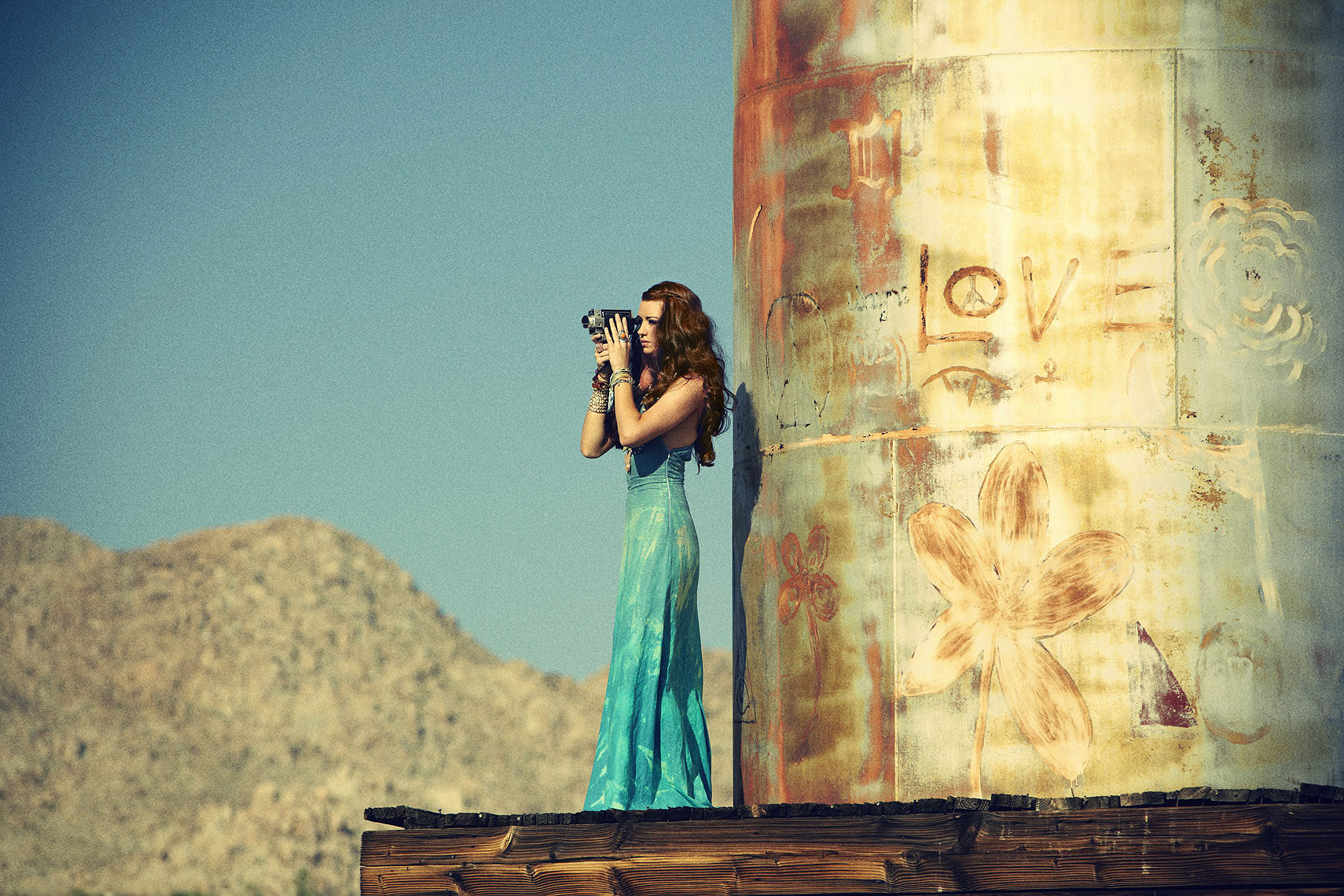 Redheaded woman standing on water tower taking pictures