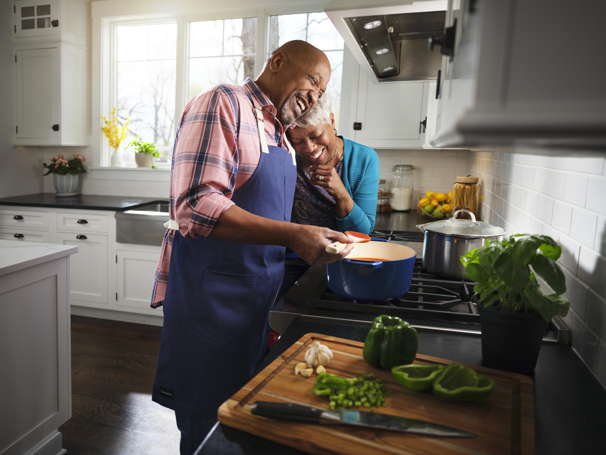 Happy black senior couple cooking in kitchen