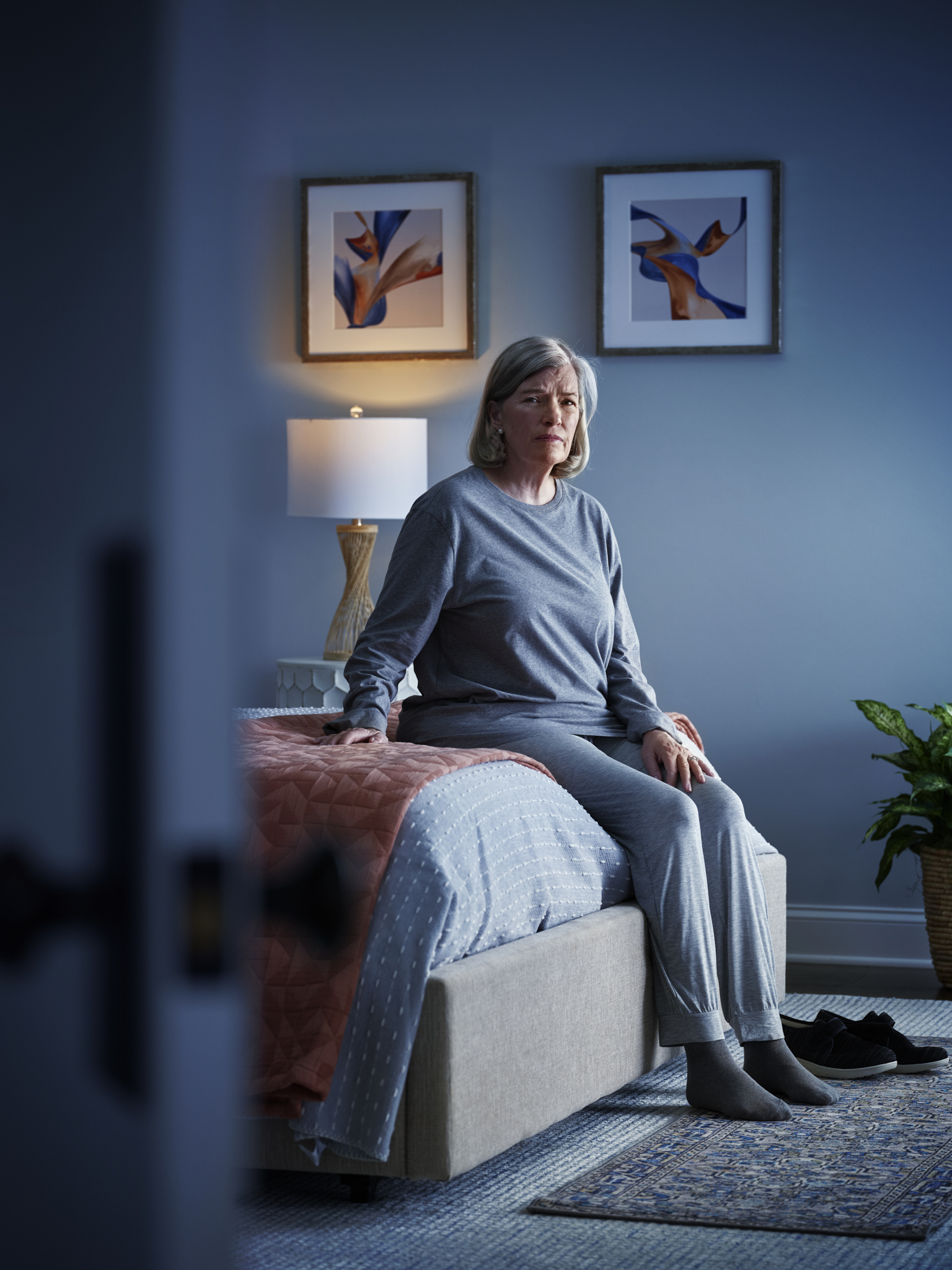depressed senior woman sitting on edge of bed